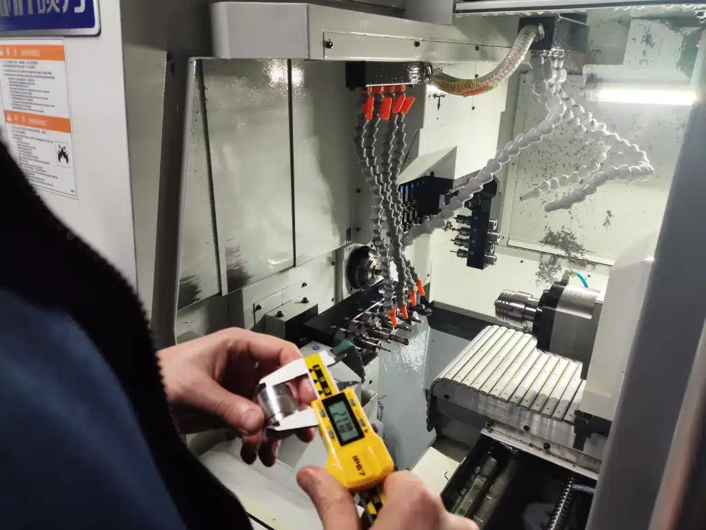 Messung eines CNC-gedrehten Bauteils mit digitaler Schieblehre an einer Drehmaschine.