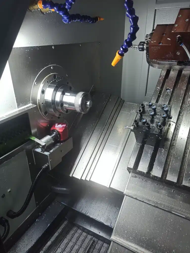Innenraum einer CNC-Maschine mit Spannfutter, Werkzeugträger und Kühlmitteldüsen.