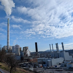 Industrieanlage mit hohen Schornsteinen und Kraftwerksgebäuden unter blauem Himmel in einer deutschen Stadt