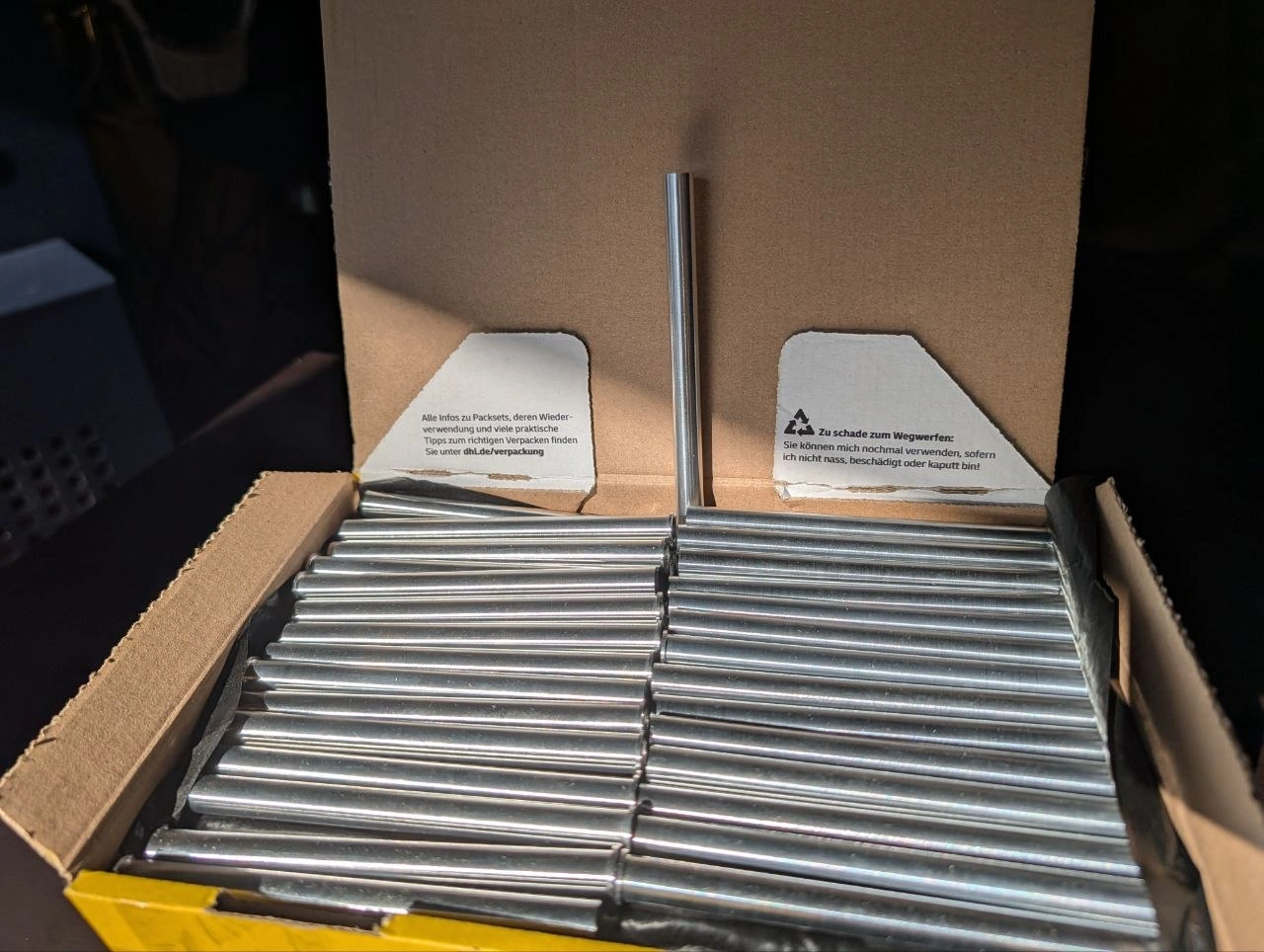 Silberfarbene Metall-Rundstäbe in Kartonverpackung für industrielle Verarbeitung und Metallbearbeitung