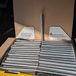 Silberfarbene Metall-Rundstäbe in Kartonverpackung für industrielle Verarbeitung und Metallbearbeitung